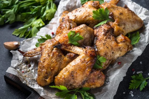 Baked chicken wings sit in tin foil.