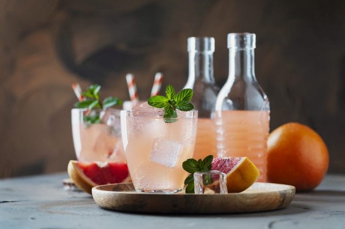 Grapefruit drinks garnished with mint sit on a table.