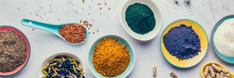 Colorful spices and herbs sit in bowls on a kitchen counter.