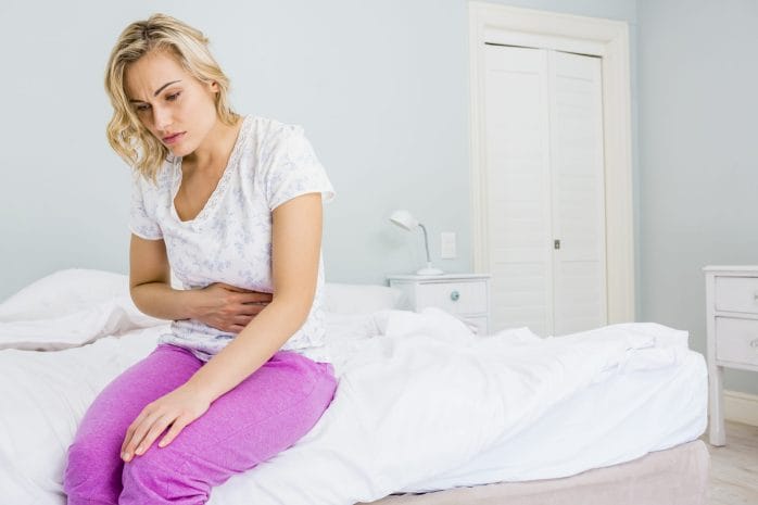 Woman holds her stomach in pain.