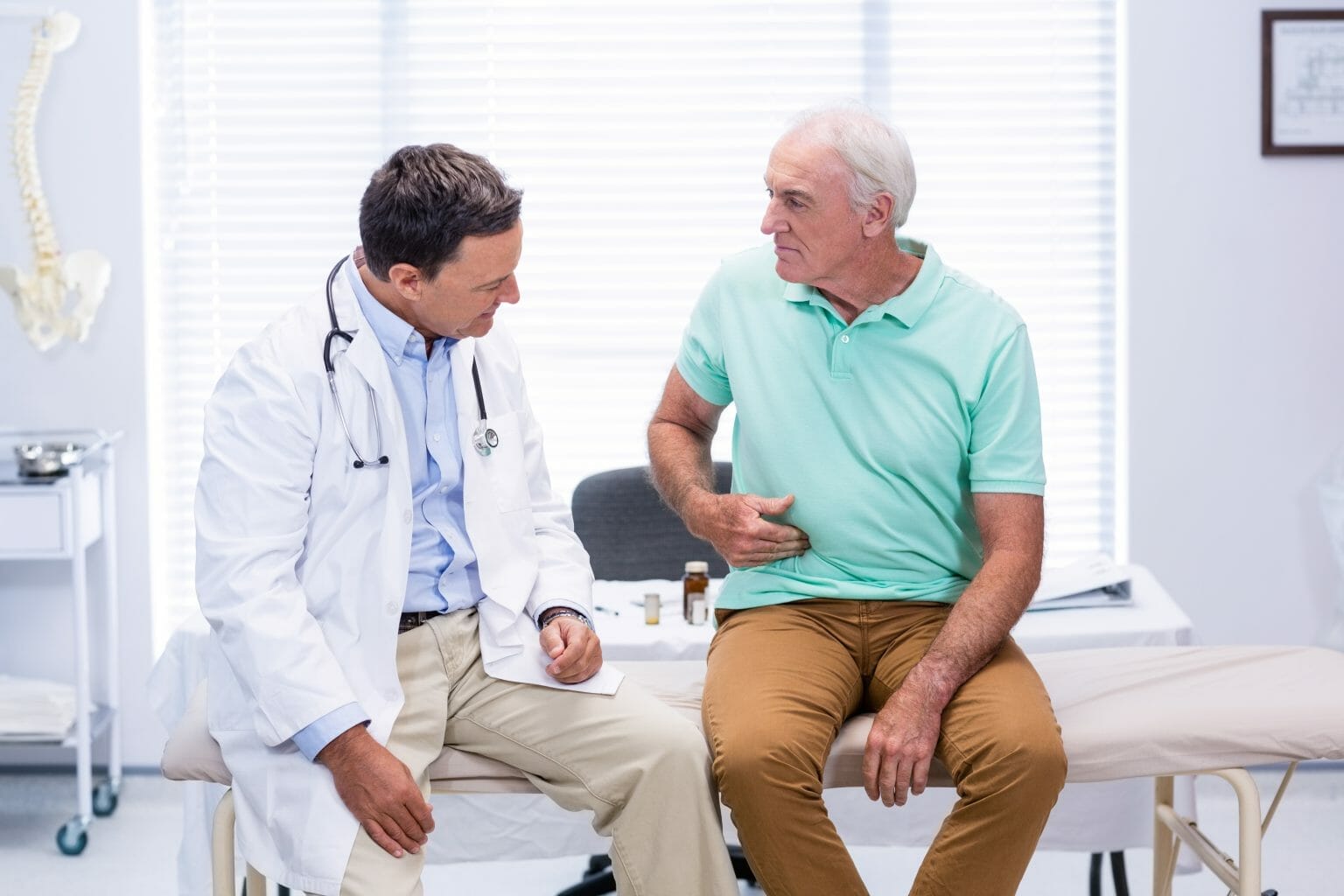 Man discussing digestive discomfort with his doctor.